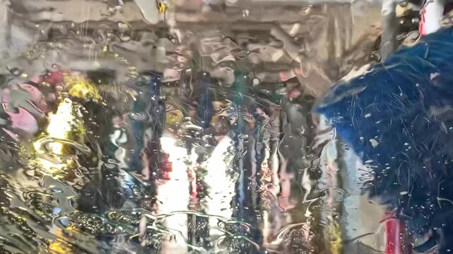 Conveyor car wash process, view from inside the vehicle: continuation of the foam wash and rinsing.
