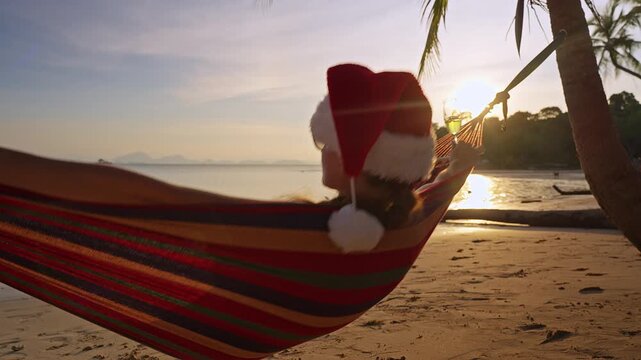 Slow Motion Close Up of a Woman Wearing a Santa Hat Relaxing in a Hammock With Sparkling Wine at Sunset on a Tropical Beach, Luxury Holiday Getaway and Peaceful Escape