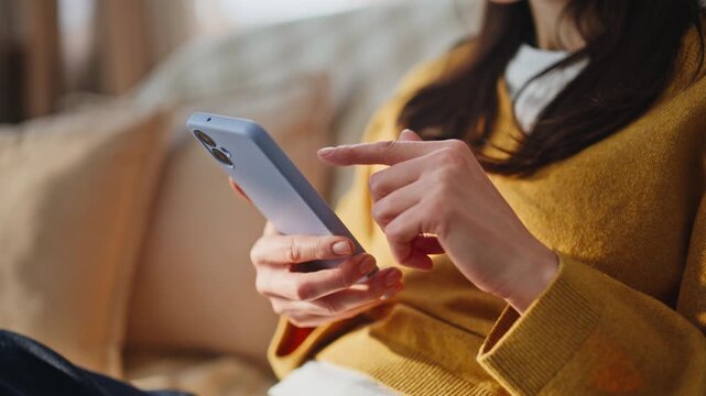 Woman fingers swiping cellphone screen choosing online purchases home closeup
