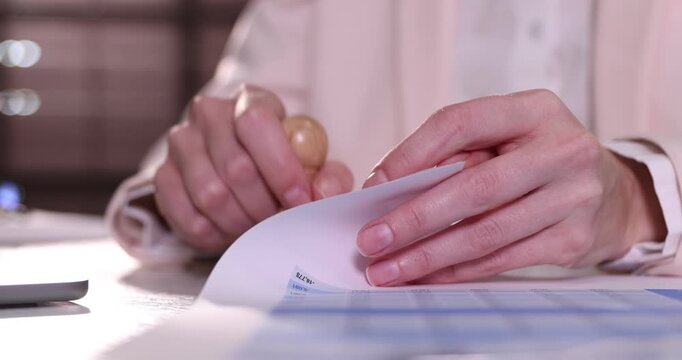 Woman stamping documents at desk indoors, closeup