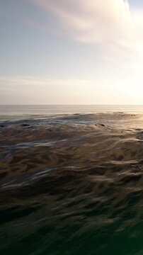 Water with gentle waves under a sunset sky. The sun casts light on the surface, creating reflections. There are no boats or people in sight.