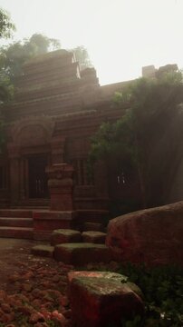 A group of people explore an old temple with stairs and stone walls. Sunlight shines through the trees, creating shadows on the ground. The atmosphere feels historical and inviting.