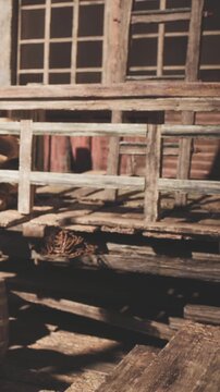 Wooden structure shows worn planks and barrels nearby. The scene is inside a building with dim light shining through the windows. Dust and signs of age are visible.