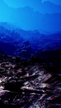 A rocky seafloor submerged underwater. The image captures the textures and shapes of the rocks and the deep blue light filtering through the water above.
