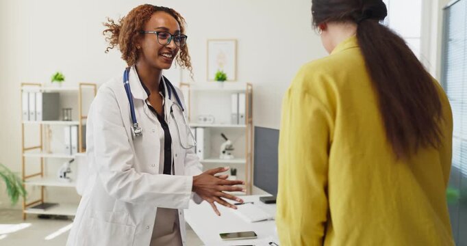 Doctor patient consultation in clinic healthcare appointment woman. The smiling physician greets the client and discusses next steps. Clear concept of professional quality medical care.