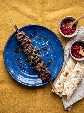 Grilled reindeer skewer on blue ceramic plate with traditional norwegian lefse bread