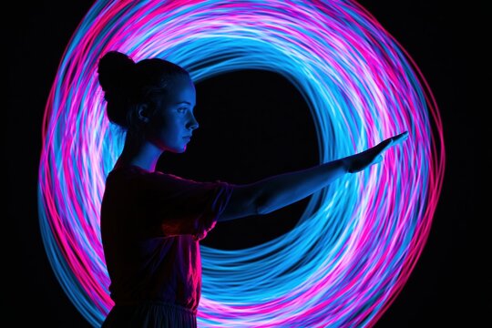 Silhouette of a woman standing in profile with a glowing neon circle light art