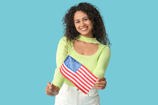 Happy young African-American woman with USA flag on blue background