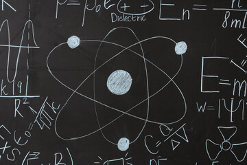 Obraz premium Drawn atomic structure and physics formulas on black chalkboard