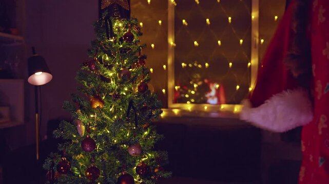 Happy Woman Dancing While Carrying a Wrapped Christmas Gift Beside a Decorated Tree With Warm Golden Lights, Joyful Holiday Celebration and Cozy Winter Home