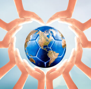Hands forming heart shape around planet earth soccer ball on soft blue background for global football sport and unity concept design