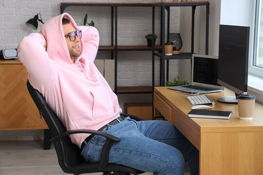 Male programmer relaxing on chair at his workspace in modern office