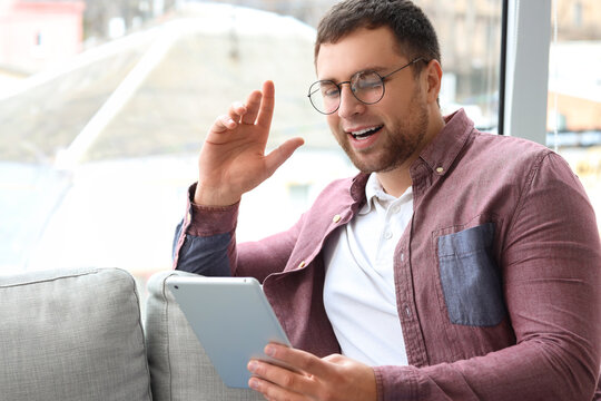 Portrait of male programmer working with tablet computer on sofa in office, closeup