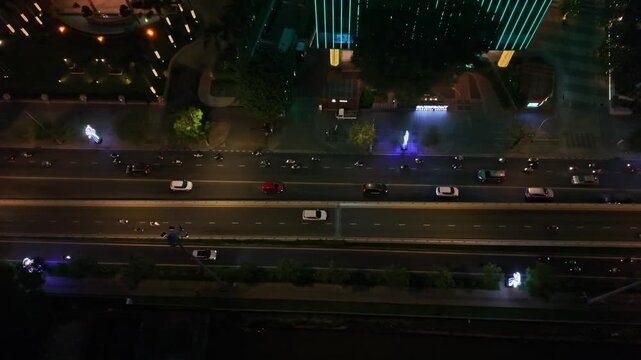 a tranquil urban landscape at night, captured from an aerial perspective, showcasing a serene cityscape with illuminated buildings, streetlights, and fountains constructed from concrete.