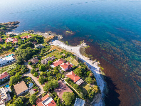 Aerial view of The Clam Beach, featuring coastal villas with red roofs, lush greenery, and clear blue sea water in Lozenets, Tsarevo, Bulgaria.