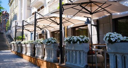 Obraz premium A summer street scene with a charming street cafe featuring a row of tables and chairs, inviting passersby to immerse themselves in the cafe's urban culture.