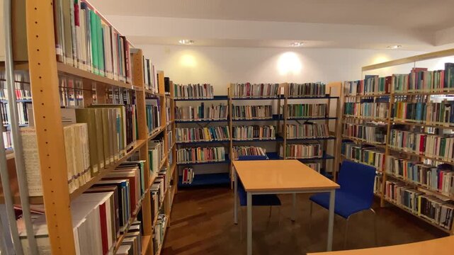 Empty library interior featuring multiple aisles of tall bookshelves filled with variouSkate park featuring ramps and rails, surrounded by colorful graffiti walls and urban buildings under a clear sky