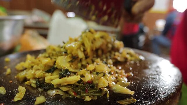Close-up of traditional Northern Thai pickled mustard greens salad, locally known as Yum Phak Kat Som, prepared with naturally fermented mustard greens, galangal, young ginger, roasted chili flakes, a