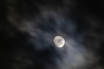Full moon in the night sky with clouds. © ric