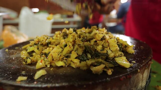 Close-up of traditional Northern Thai pickled mustard greens salad, locally known as Yum Phak Kat Som, prepared with naturally fermented mustard greens, galangal, young ginger, roasted chili flakes, a