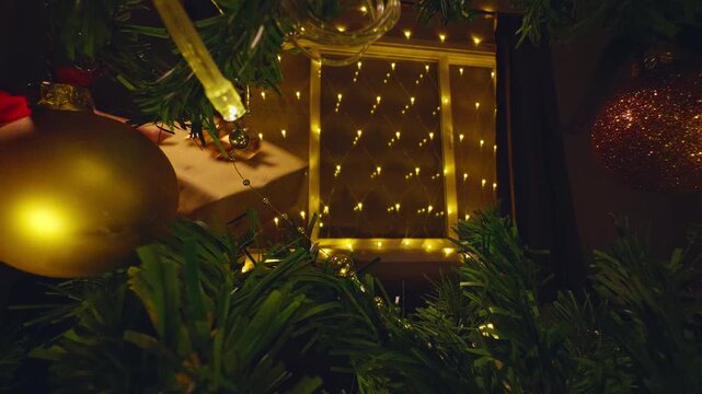 View From Inside a Christmas Tree as a Wrapped Holiday Gift Is Passed Between Two People Surrounded by Warm Fairy Lights, Christmas Giving and Family Celebration