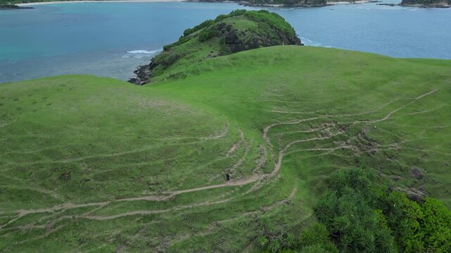 Woman Resting On Hilltop Overlooking Turquoise Bay And Narrow Headland Seated Figure Gazes At Calm Water, Soft Light,Aerial Composition Evokes Peace And Contemplation, Bukit Merese,Lombok, Tanjung Ann