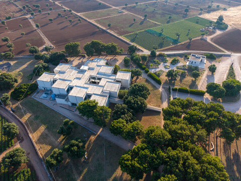 Aerial view of the Parco Archeologico di Egnazia museum building surrounded by olive groves and agricultural fields in Fasano, Puglia, Italy.
