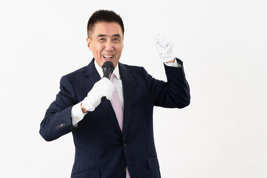 マイクを持ちながら選挙演説をするシニア男性