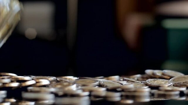 Woman Pouring Argentine Peso Coins From Glass Jar Onto Table And Picking One Up