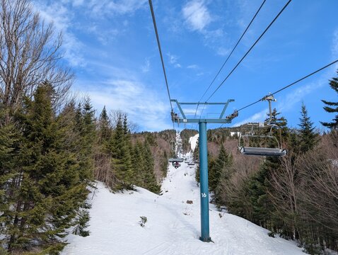 Skiing in winter - chairlift gondola and ski slopes for skiing and snowboarding  between trees on frosty day with beautiful views in  mountains