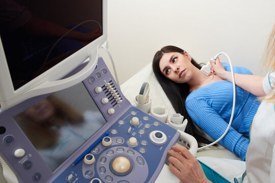 Doctor using ultrasound scanning machine examining female neck