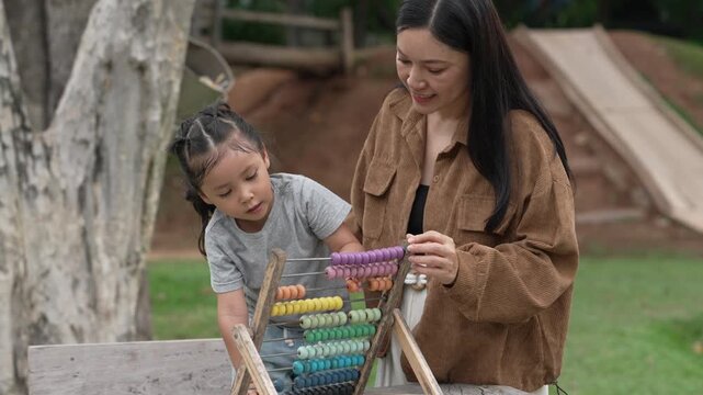 slow motion of preschool child girl learning and playing colorful wooden abacus with mother