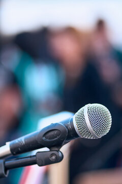 A close-up of a microphone on a stage, positioned for use by a speaker. Live event, audio and sound equipment.