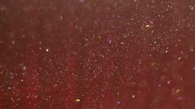 Defocused shine particles. Light glitter dots. Red pink stream blend rainbow powder. Art color bokeh luminosity abstract glossy background.