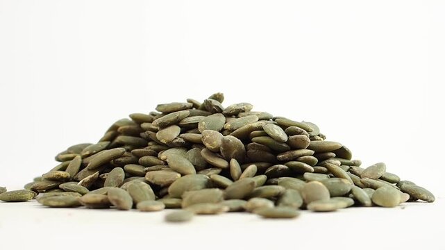 Pumpkin seeds stacked on a white surface in a close view