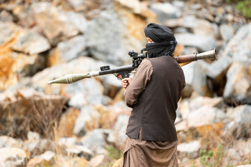 Fototapeta premium Armed militant aiming a rocket launcher during a simulated conflict scenario in rocky outdoor terrain