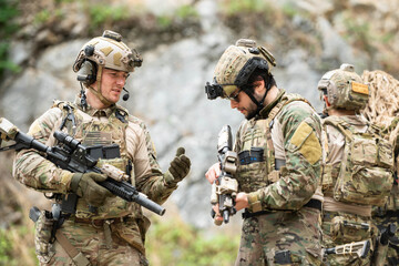 Fototapeta premium Military personnel discuss equipment and mission details during a tactical field briefing