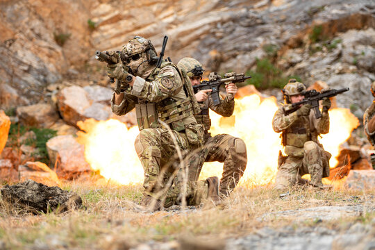 Elite soldiers advance through a combat training scenario with simulated explosions