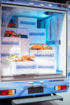 Open back of refrigerated delivery truck loaded with frozen and chilled seafood in boxes.