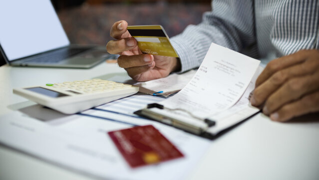 close-up shot, man hand holding credit card calculate expenses from receipt and bills before paying credit card debt