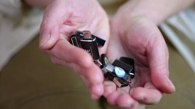 Person opening hands revealing a pile of usb adapters. Cupped hands opening slowly to show a pile of various usb adapters and converters, including usb-c, micro usb, and type-a connectors