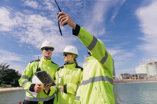 Engineers collaborating at oil and gas refinery analyzing data and ensuring safety protocols in industrial environment