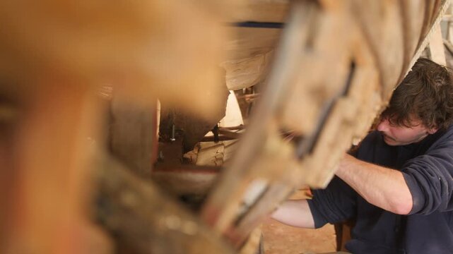 Traditional wooden boat building hammering copper rivets