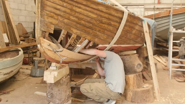 Young man copper riveting planks on classic clinker boat repair