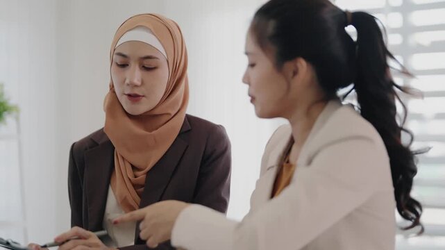 Two business colleagues multiethnic working in office, asian muslim