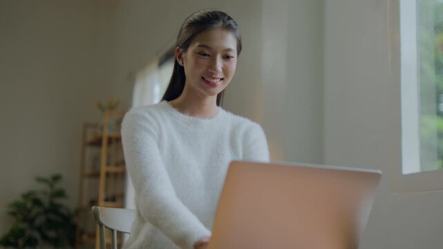 Woman works remotely from living room using laptop comfortably