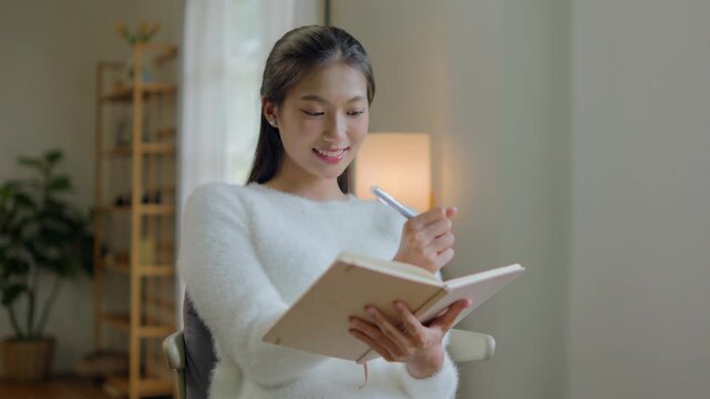 woman writing diary planning on notebook at home