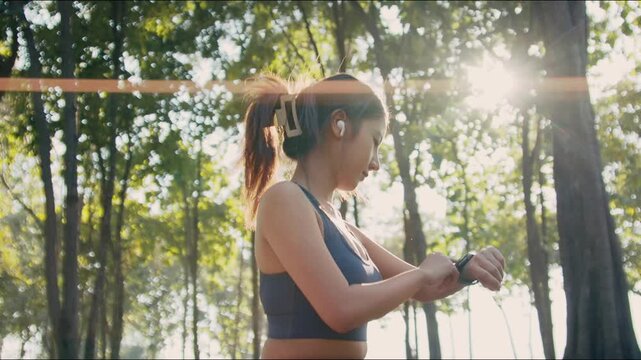 asian female athlete using smartwatch at park