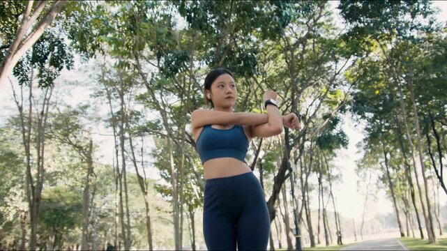 Asian woman stretches before outdoor fitness session in park