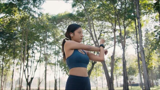 Asian woman stretches before outdoor fitness session in park